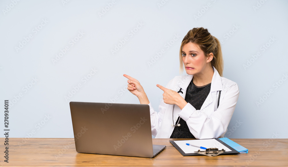 Blonde doctor woman frightened and pointing to the side Blonde doctor woman frightened and pointing to the side