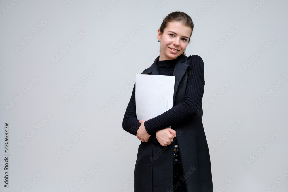Photo portrait of a beautiful smiling brunette business woman with a folder on a white background in a black business suit with long beautiful dark hair in the studio. Photo portrait of a beautiful smiling brunette business woman with a folder on a white background in a black business suit with long beautiful dark hair in the studio.