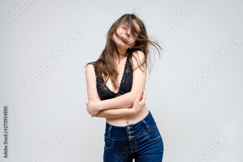 Photo portrait of a beautiful smiling brunette woman girl on a white background in jeans and a blouse with long beautiful flowing dark hair in the studio. © Вячеслав Чичаев
