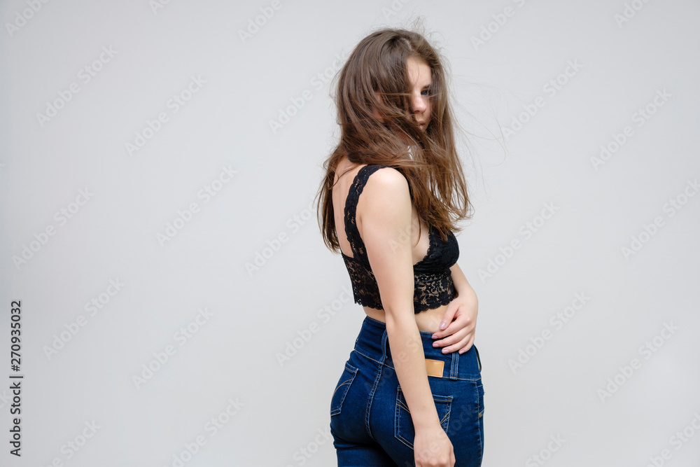 Photo portrait of a beautiful smiling brunette woman girl on a white background in jeans and a blouse with long beautiful flowing dark hair in the studio. Photo portrait of a beautiful smiling brunette woman girl on a white background in jeans and a blouse with long beautiful flowing dark hair in the studio.