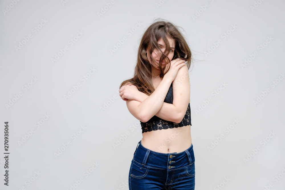 Photo portrait of a beautiful smiling brunette woman girl on a white background in jeans and a blouse with long beautiful flowing dark hair in the studio. Photo portrait of a beautiful smiling brunette woman girl on a white background in jeans and a blouse with long beautiful flowing dark hair in the studio.