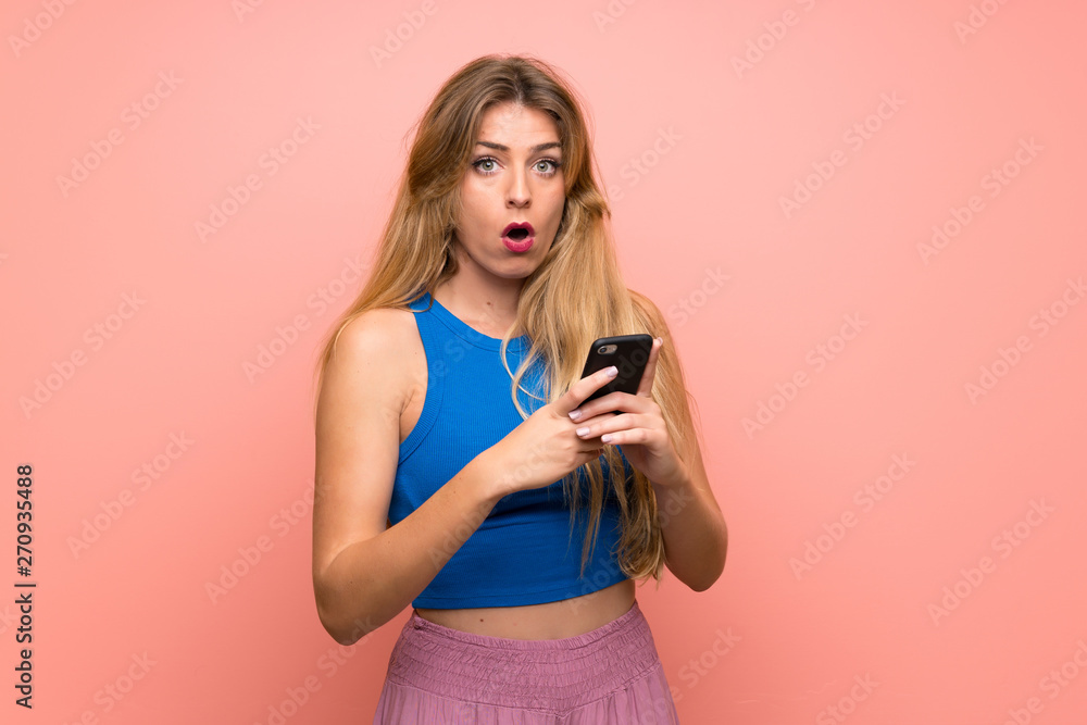 Young blonde woman over isolated pink background surprised and sending a message Young blonde woman over isolated pink background surprised and sending a message