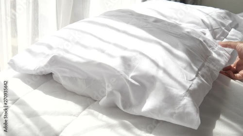 Hands bedding white blanket with natural light from window, slow motion