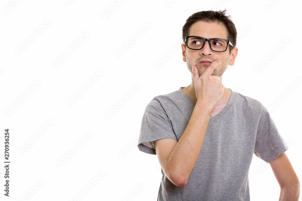Studio shot of young man wearing eyeglasses while thinking and l Studio shot of young man wearing eyeglasses while thinking and l