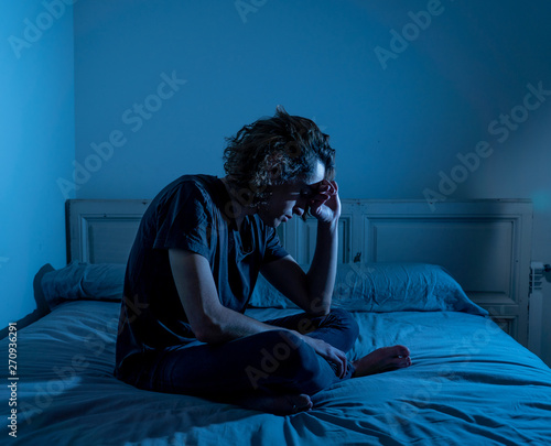Canvas Print Desperate lonely teenager man suffering from depression sitting alone on bed
