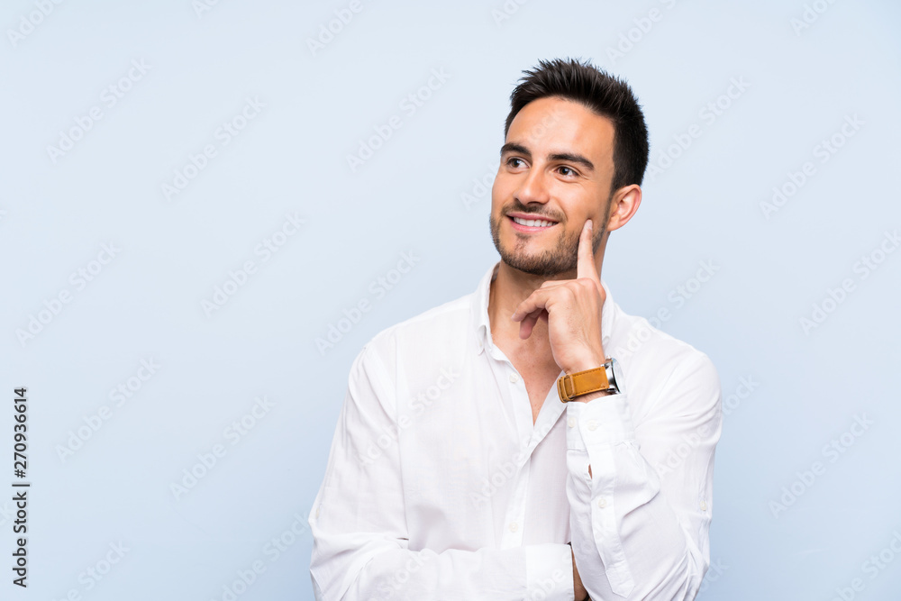 Handsome young man over isolated blue background thinking an idea while looking up Handsome young man over isolated blue background thinking an idea while looking up