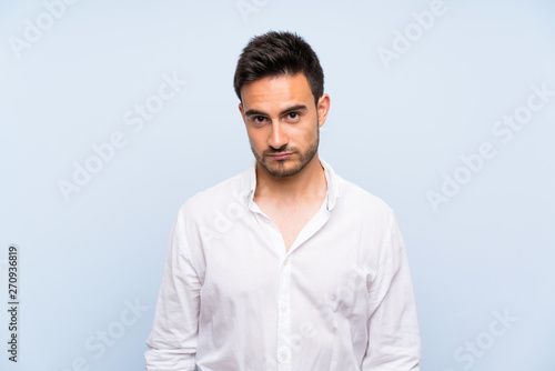 Handsome young man over isolated blue background with sad and depressed expression