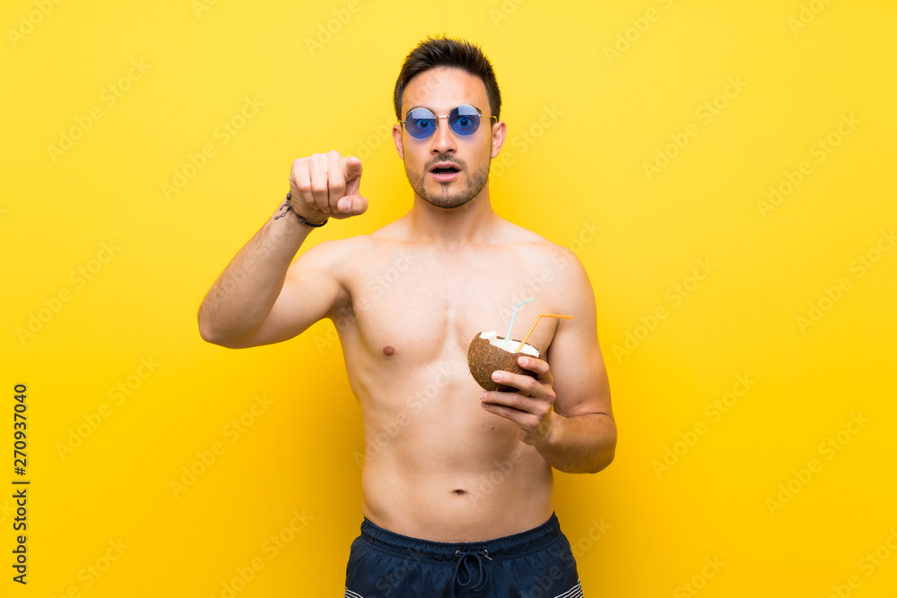 Handsome young man in summer clothes surprised and pointing front Handsome young man in summer clothes surprised and pointing front