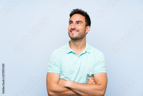 Handsome young man over isolated background looking up while smiling