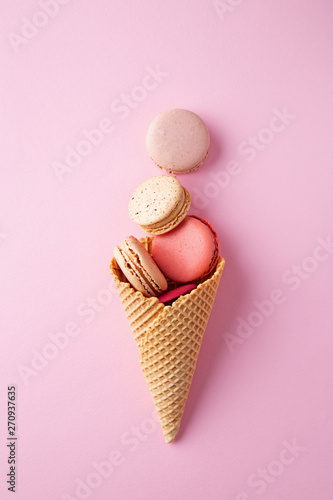 Macarons in a ice cream cone on a pink background viewed from above. Top view