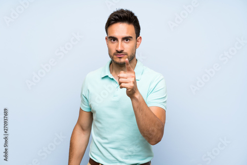 Handsome young man over isolated background frustrated and pointing to the front