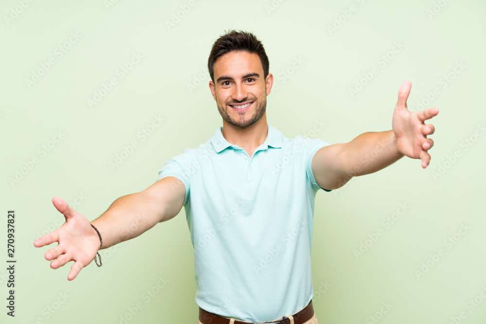 Handsome young man over isolated background presenting and inviting to come with hand Handsome young man over isolated background presenting and inviting to come with hand