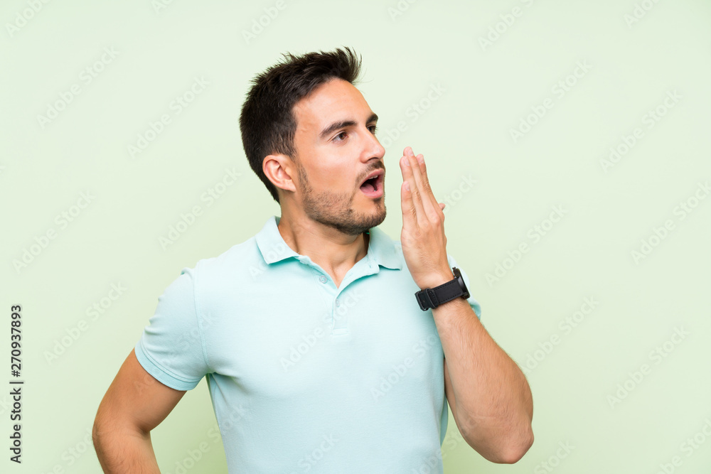 Handsome young man over isolated background yawning and covering wide open mouth with hand Handsome young man over isolated background yawning and covering wide open mouth with hand