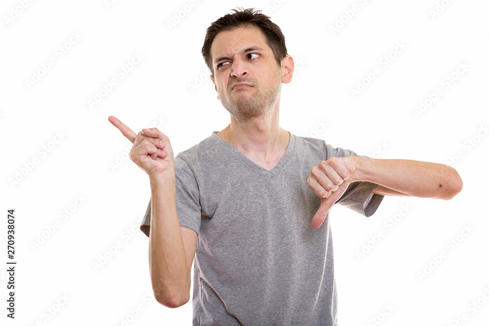 Studio shot of disgusted young man pointing to the left and givi Studio shot of disgusted young man pointing to the left and givi