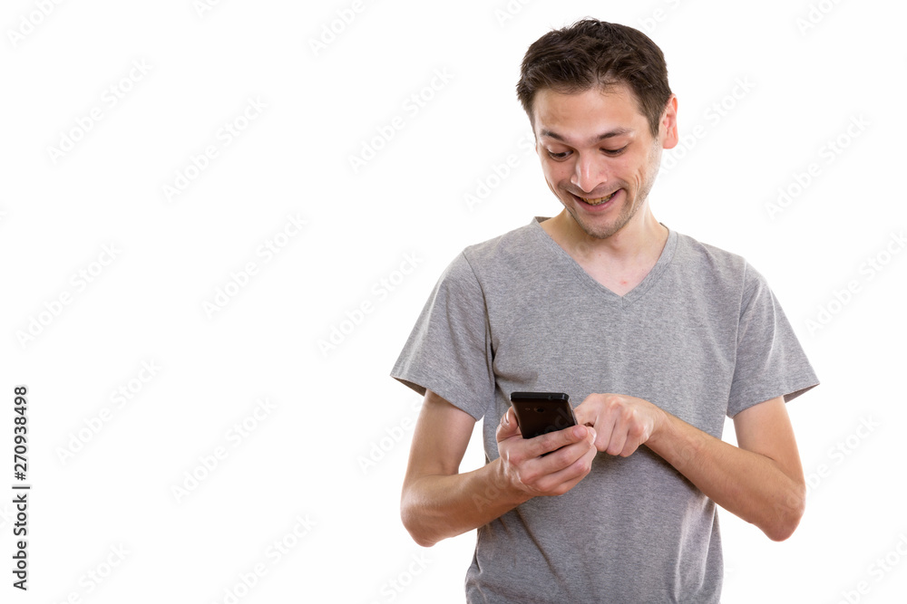 Studio shot of happy young man smiling while using mobile phone Studio shot of happy young man smiling while using mobile phone