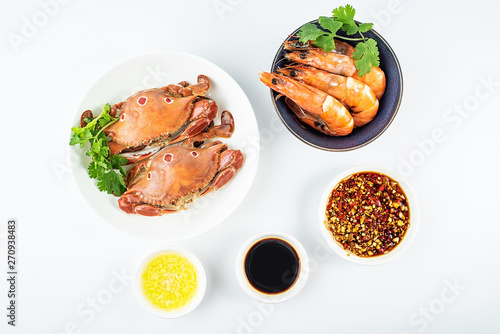A dish of steamed three-pointed crab and a bowl of boiled shrimp on a white background