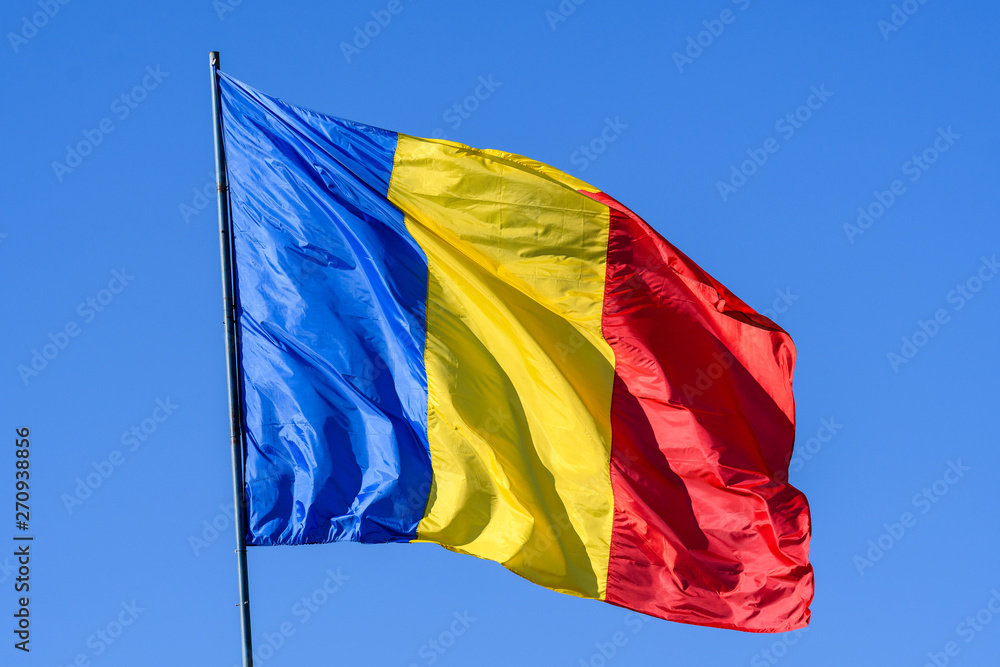 Romanian flag blowing in the wind in direct sunlight towards clear blue sky Romanian flag blowing in the wind in direct sunlight towards clear blue sky