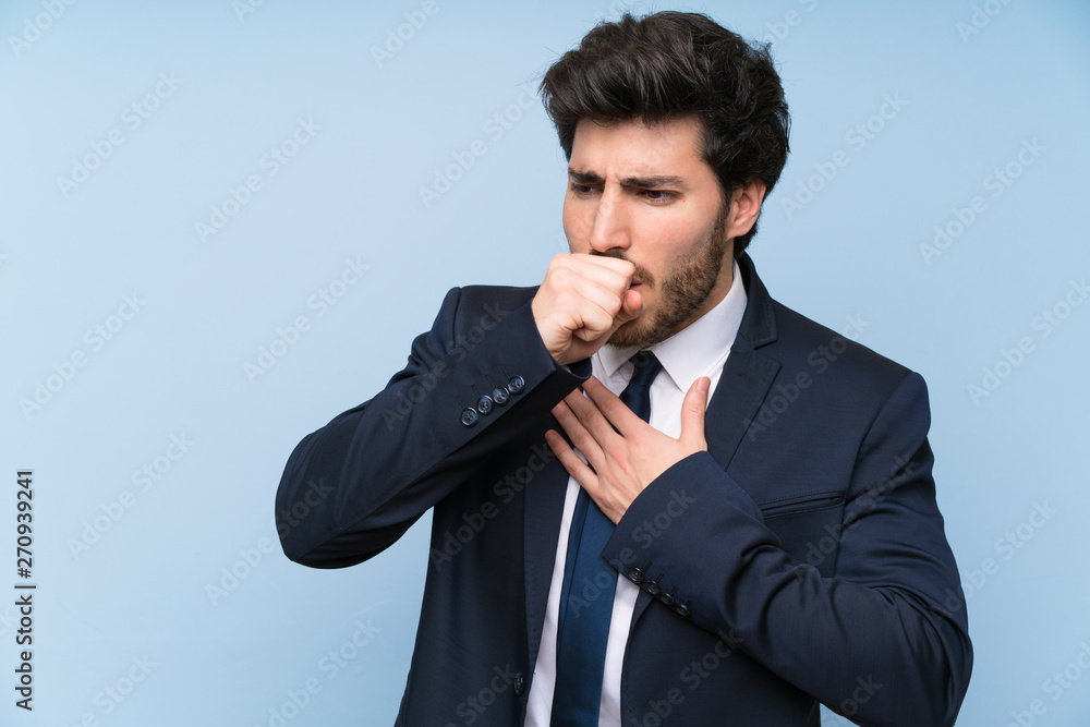 Businessman over isolated blue wall is suffering with cough and feeling bad Businessman over isolated blue wall is suffering with cough and feeling bad