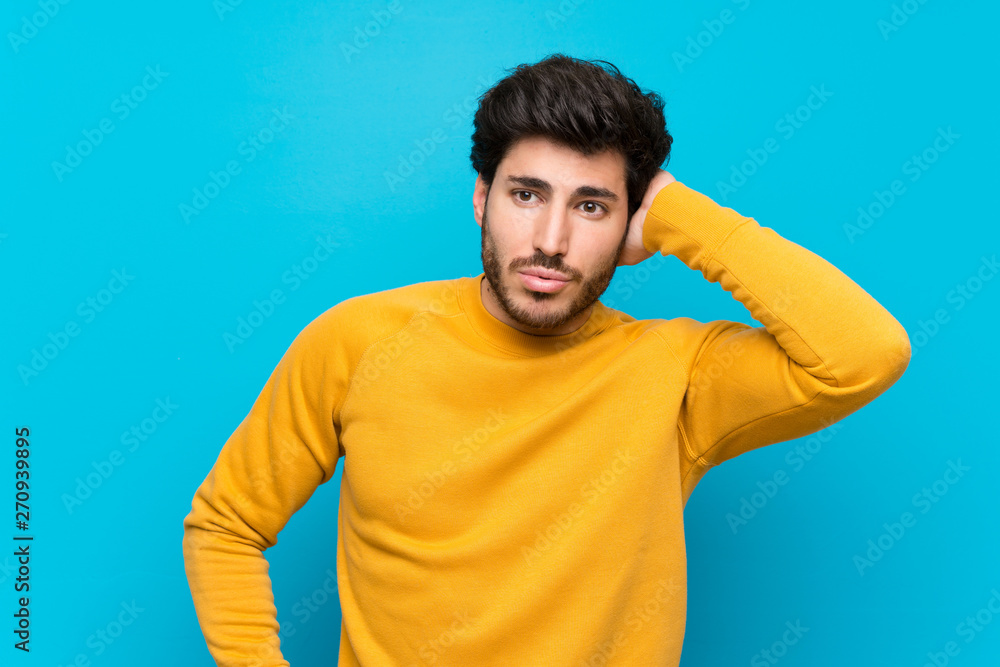 Handsome over isolated blue wall having doubts Handsome over isolated blue wall having doubts