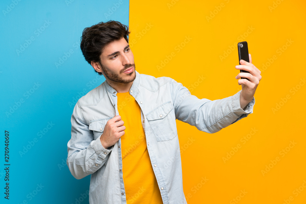 Handsome over isolated colorful background making a selfie Handsome over isolated colorful background making a selfie