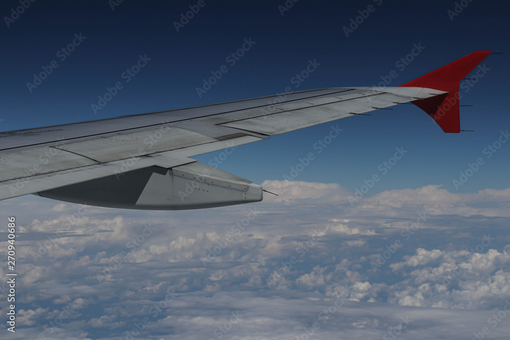The right wing of the aircraft against the white clouds and blue The right wing of the aircraft against the white clouds and blue