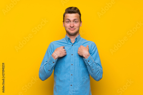 Blonde man over isolated yellow wall with surprise facial expression