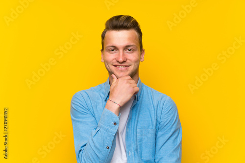 Blonde handsome man over isolated wall laughing