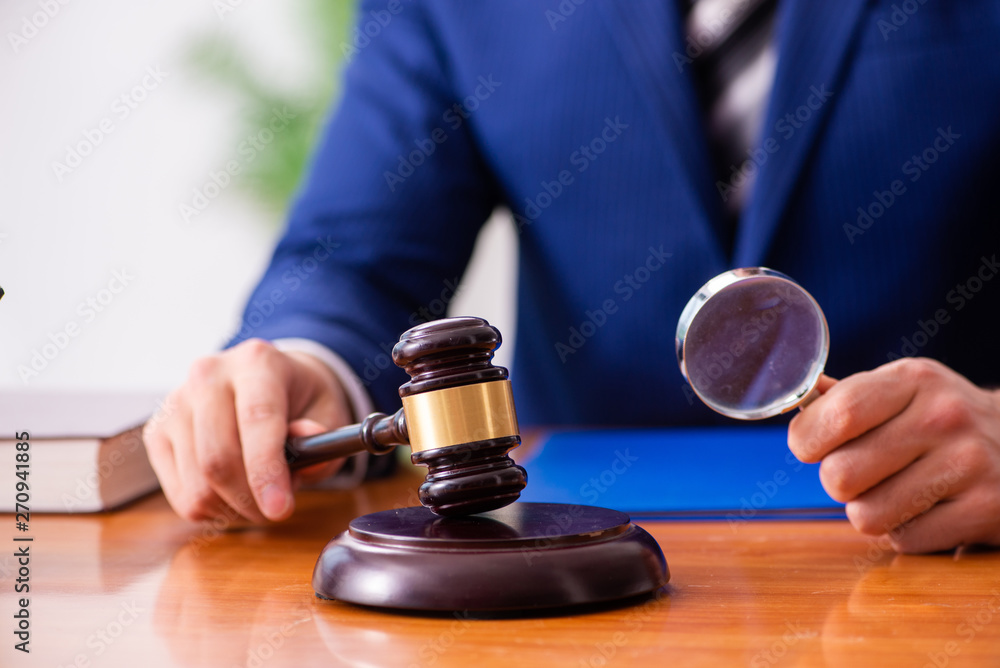 Young male judge sitting in courtroom Young male judge sitting in courtroom