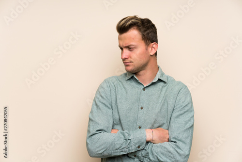 Blonde handsome man over isolated wall standing and thinking an idea