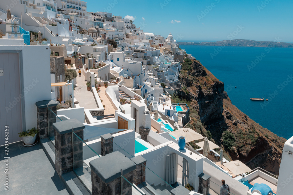 Santorini, Greece. Picturesque view of traditional cycladic Santorini houses on small street with flowers in foreground. Location: Oia village, Santorini, Greece. Vacations background.