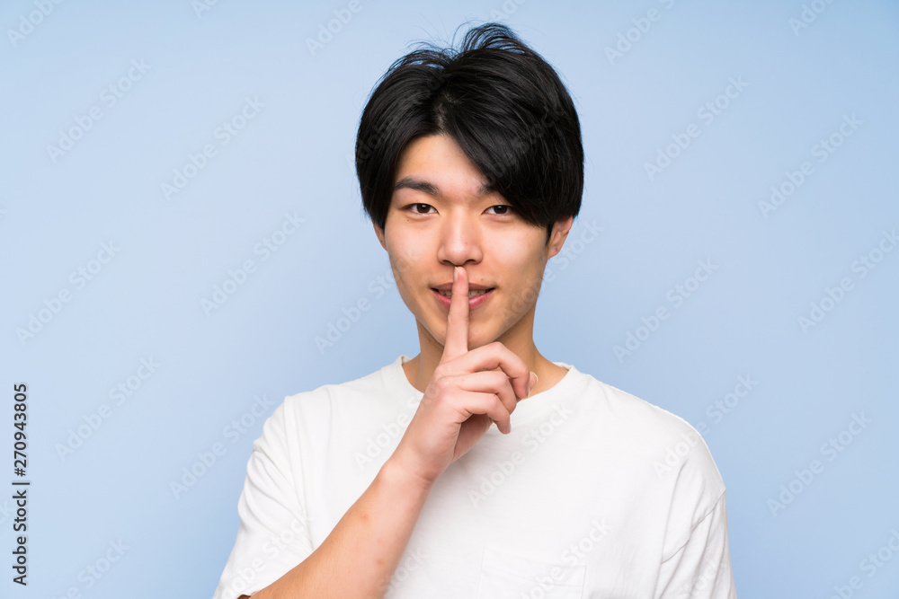 Asian man on isolated blue background doing silence gesture Asian man on isolated blue background doing silence gesture