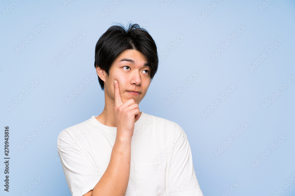 Asian man on isolated blue background thinking an idea Asian man on isolated blue background thinking an idea
