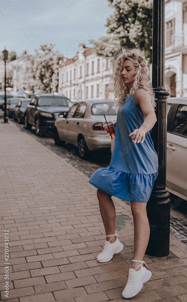 Naklejka premium Girl street style. Fashion young beautiful woman posing on city street. Urban. Sundress. Lifestyle. Moment. Holidays. Summer time
