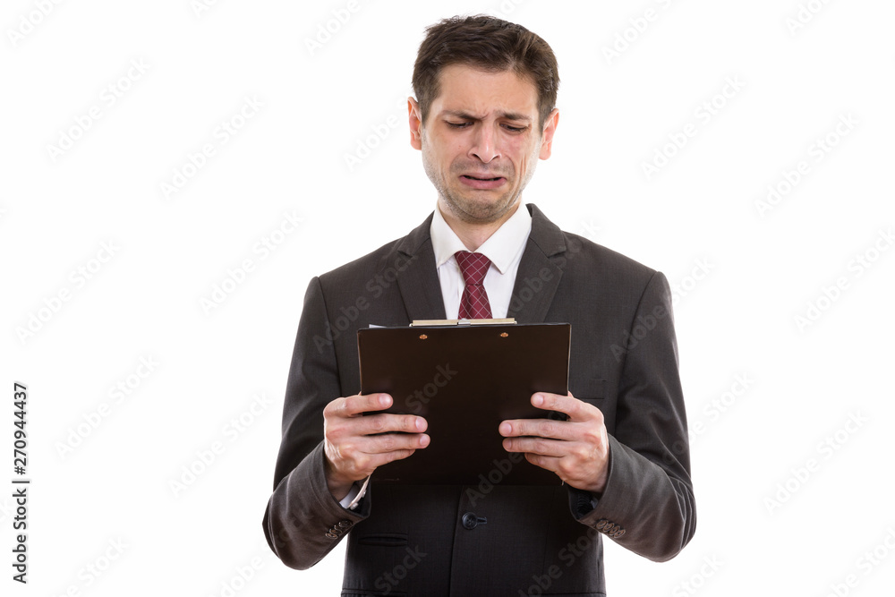 Studio shot of sad young businessman reading on clipboard Studio shot of sad young businessman reading on clipboard