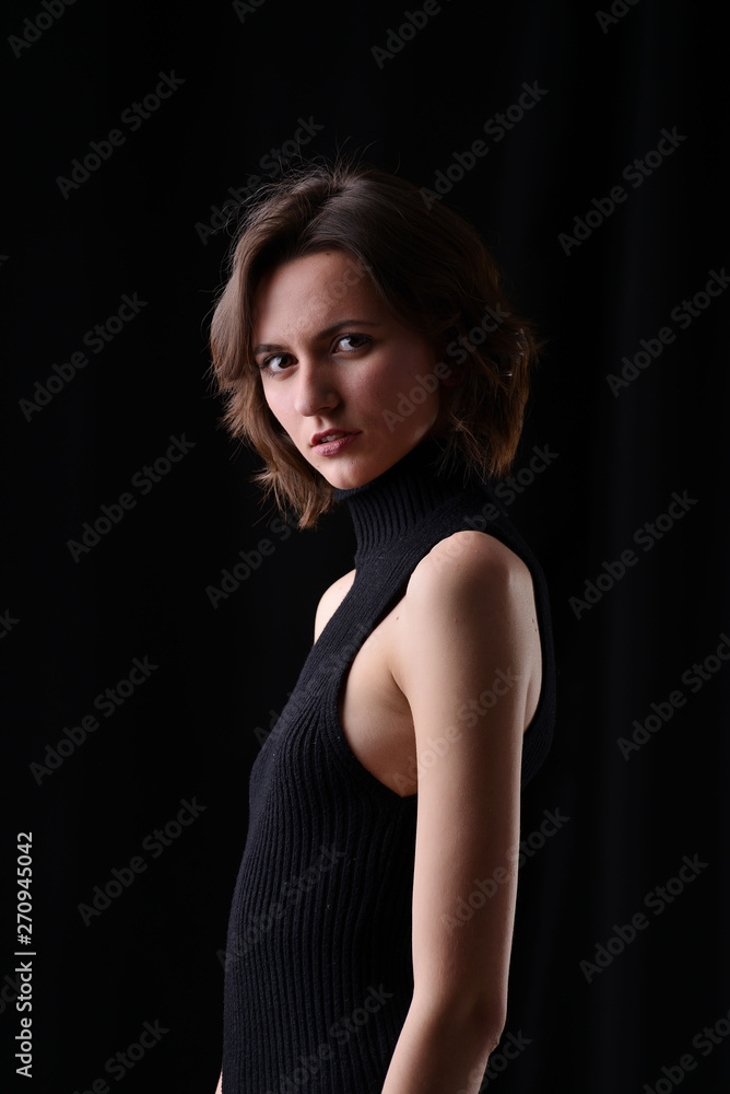 Young beautiful dark-haired girl in a black T-shirt on a dark background Young beautiful dark-haired girl in a black T-shirt on a dark background
