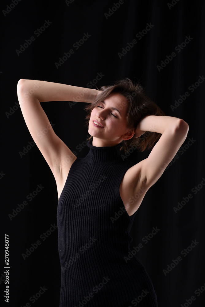 Young beautiful dark-haired girl in a black T-shirt on a dark background Young beautiful dark-haired girl in a black T-shirt on a dark background