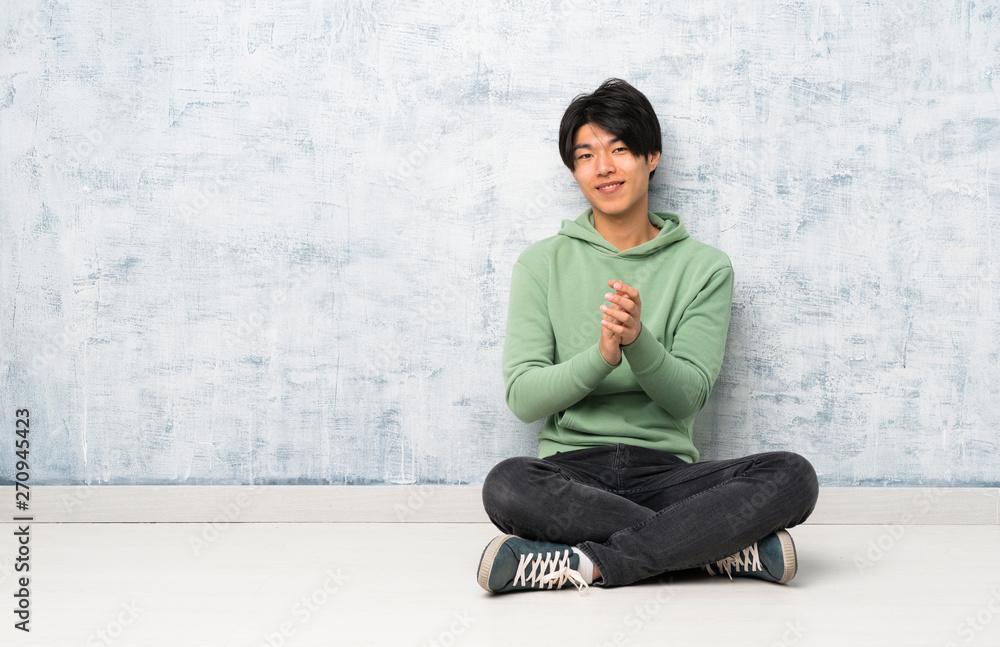 Asian man sitting on the floor applauding after presentation in a conference Asian man sitting on the floor applauding after presentation in a conference