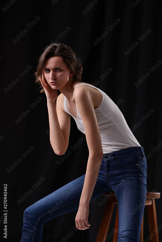 young beautiful dark-haired girl in a white vest on a dark background