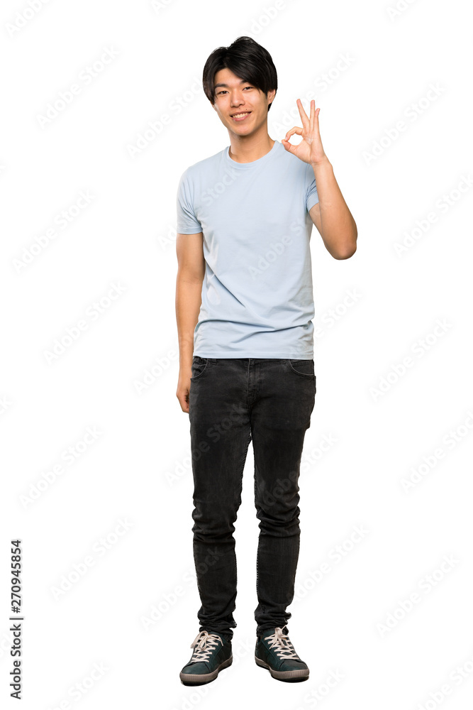 A full-length shot of a Asian man with blue shirt showing ok sign with fingers over isolated white background A full-length shot of a Asian man with blue shirt showing ok sign with fingers over isolated white background