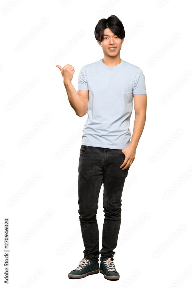 A full-length shot of a Asian man with blue shirt pointing to the side to present a product over isolated white background A full-length shot of a Asian man with blue shirt pointing to the side to present a product over isolated white background