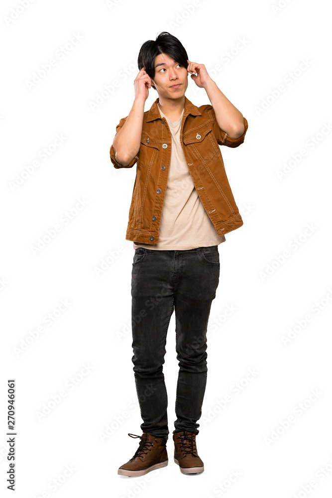 A full-length shot of a Asian man with brown jacket having doubts and thinking over isolated white background A full-length shot of a Asian man with brown jacket having doubts and thinking over isolated white background