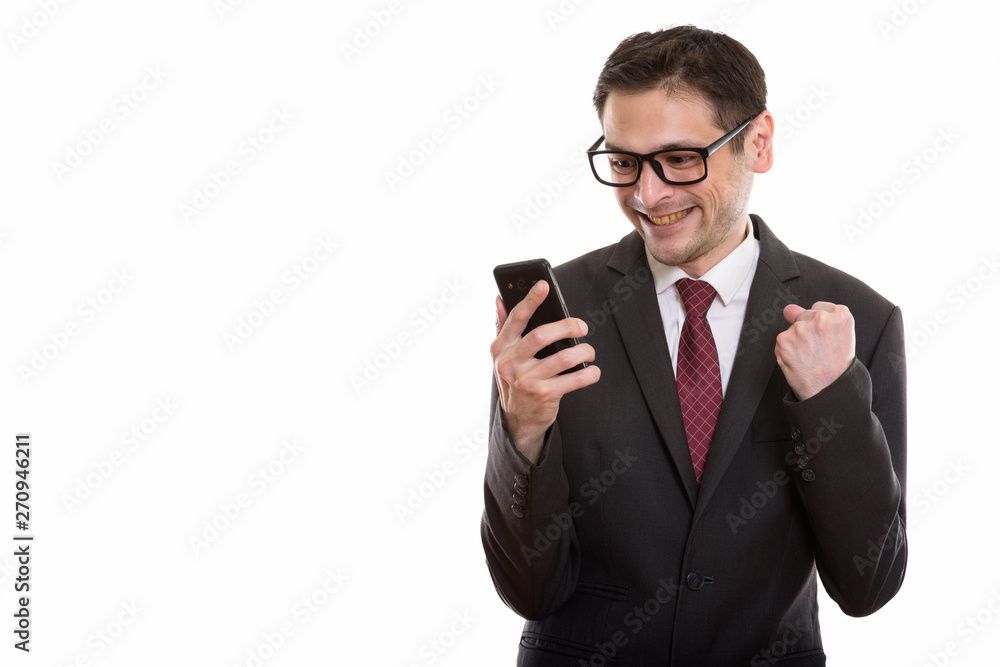 Studio shot of happy young businessman smiling while using mobil Studio shot of happy young businessman smiling while using mobil