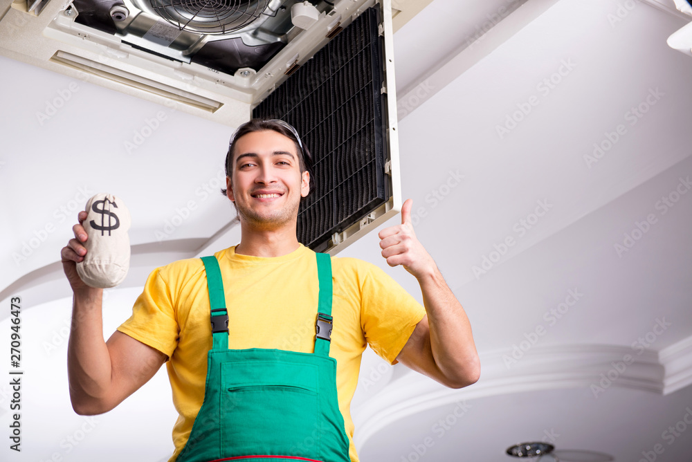 Young repairman repairing ceiling air conditioning unit Young repairman repairing ceiling air conditioning unit
