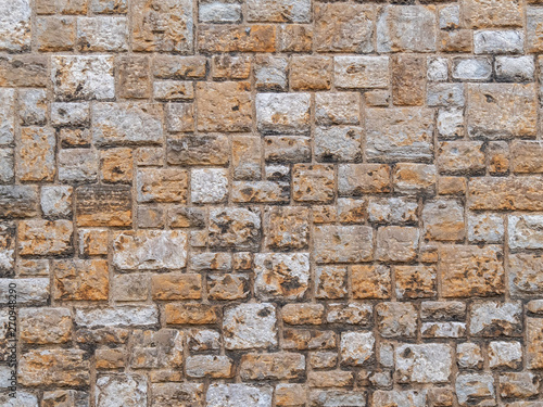 Pattern gray color of old style design decorative uneven cracked real stone wall surface with cement. Old beige stone wall background texture. Part of a stone wall, for background or texture.