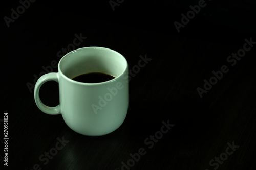 White coffee cup, black coffee on black background with light and shadow