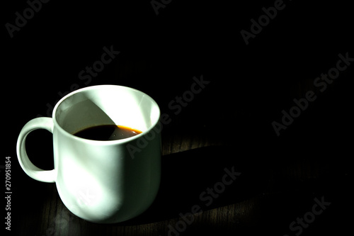 White coffee cup, black coffee on black background with light and shadow