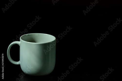 White coffee cup, black coffee on black background with light and shadow