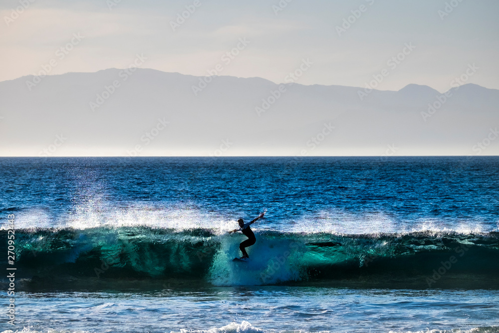 teenager surfing at the wave in tenerife playa de las americas - white wetsuits and beautiful and perfect wave