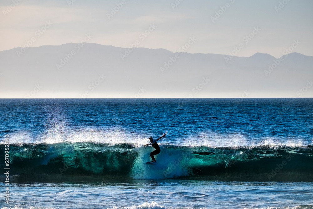 Obraz premium teenager surfing at the wave in tenerife playa de las americas - white wetsuits and beautiful and perfect wave