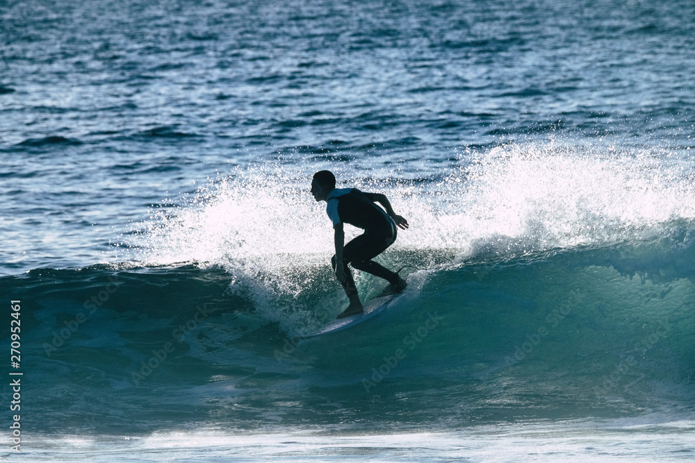 teenager surfing at the wave in tenerife playa de las americas - white and black wetsuits and beautiful and small wave